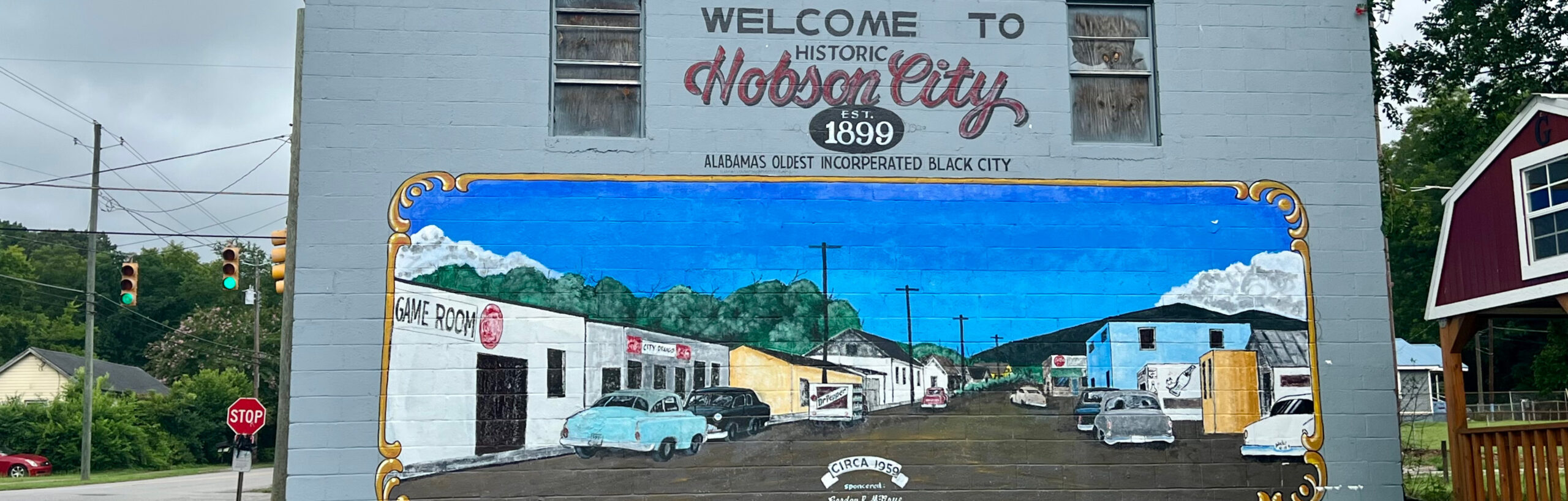 Mural depicting a 1959 street scene of Hobson City, with old fashioned cars and vibrant buildings. Above the image, the words "Welcome to History Hobson City EST. 1899 Alabama's oldest incorporated Black City" are painted