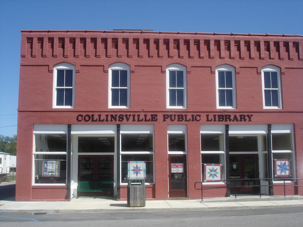 The front of the Collinsville Public Library. It is a red brick building with several windows on the second floor and large glass doors on teh first.