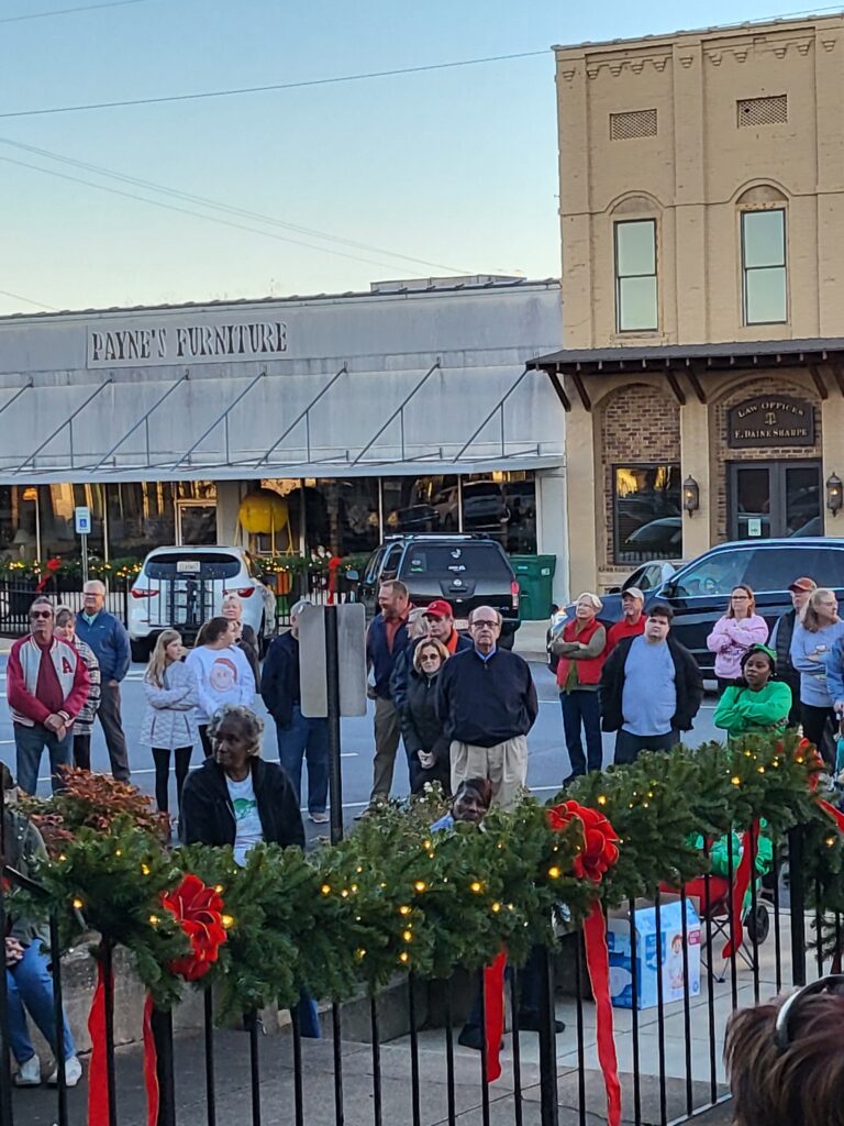 Dadeville residents stand in the downtown. There are holiday decorations.