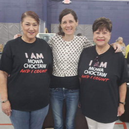 MOWA Community Liaison Maggie Rivers stands with two women. Maggie and one of the women are wearing a shirt that says "I am MOWA Choctaw and I count"