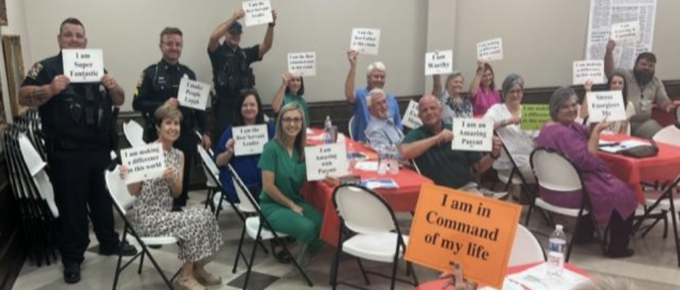 Dr. Earl Suttle leads an exercise at the Haleyville kickoff. Attendees are holding up sheets of paper that have empowering phrases written on them.