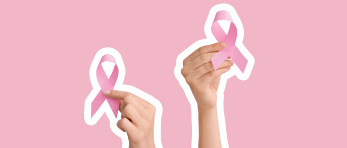 A picture of two hands holding up pink ribbons.